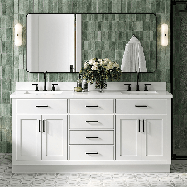 White double sink vanity with silver hardware, marble top, and twin mirrors against a green tiled wall.
