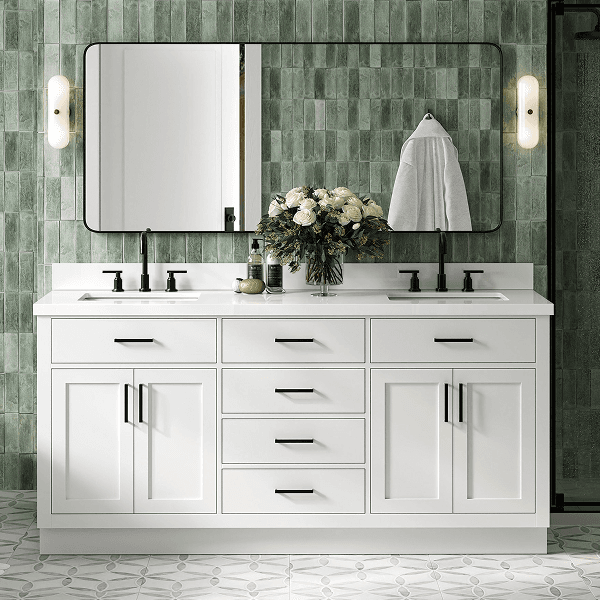 White double sink bathroom vanity White double sink vanity with silver hardware, marble top, and twin mirrors against a green tiled wall.