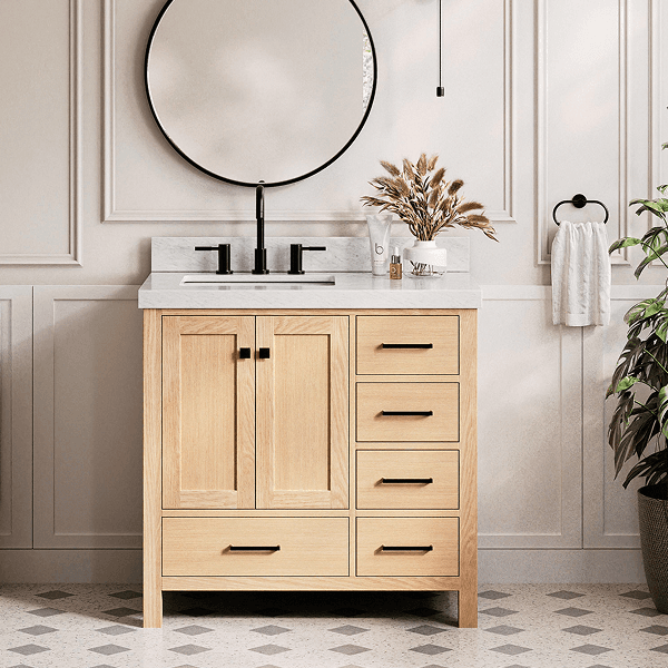 Natural oak single sink bathroom vanity Natural oak single sink vanity with black hardware, round mirror, and marble top styled in a neutral bathroom.