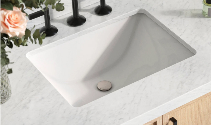 Close-up of rectangular porcelain sink with marble countertop and matte black faucet in the Kelly Vanity Collection.