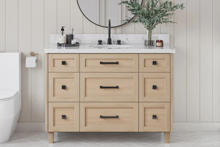 Natural oak vanity with black hardware and marble top, styled with vertical panel walls and round mirror.