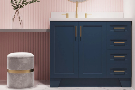 Midnight blue vanity with white top and brushed gold hardware, set against blush pink panel wall with modern stool.